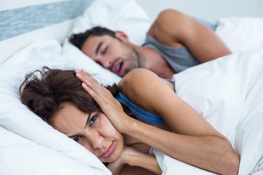 Ένας άνδρας ροχαλίζει, η γυναίκα κλείνει τα αυτιά της