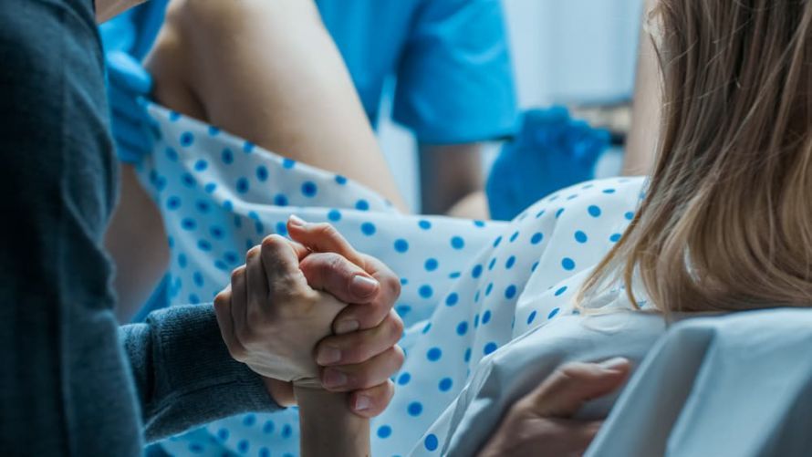 Gebärende Frau, der Mann hält ihre Hand. A woman in labor; her husband is holding her hand.