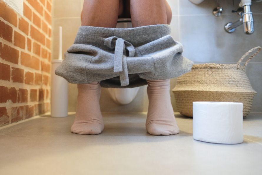 Person sitzt auf der Toilette Person sitzt auf der Toilette