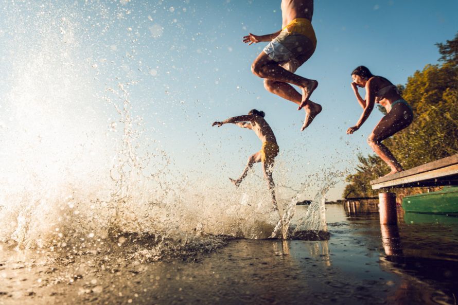 Menschen springen in einen Badesee People are jumping into a swimming lake