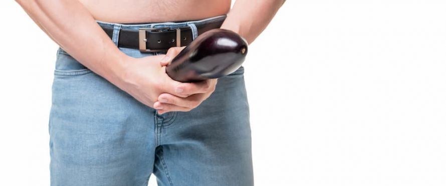 Mann hält sich Melanzani vor den Schritt Mann hält sich Melanzani vor den Schritt