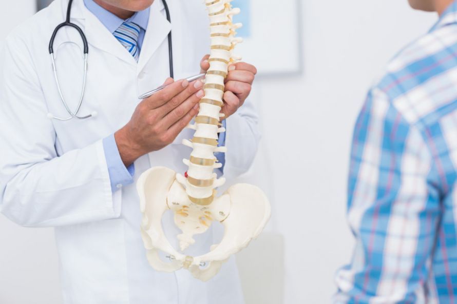 Arzt zeigt Patienten ein Modell der Wirbelsäule Ο γιατρός δείχνει στους ασθενείς ένα μοντέλο της σπονδυλικής στήλης